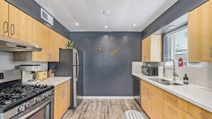 Eine moderne Küche mit Holzausstattung, Edelstahlgeräten und dekorativer Wandkunst.