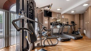 A gym with cardio machines, weight machines, and a TV screen.