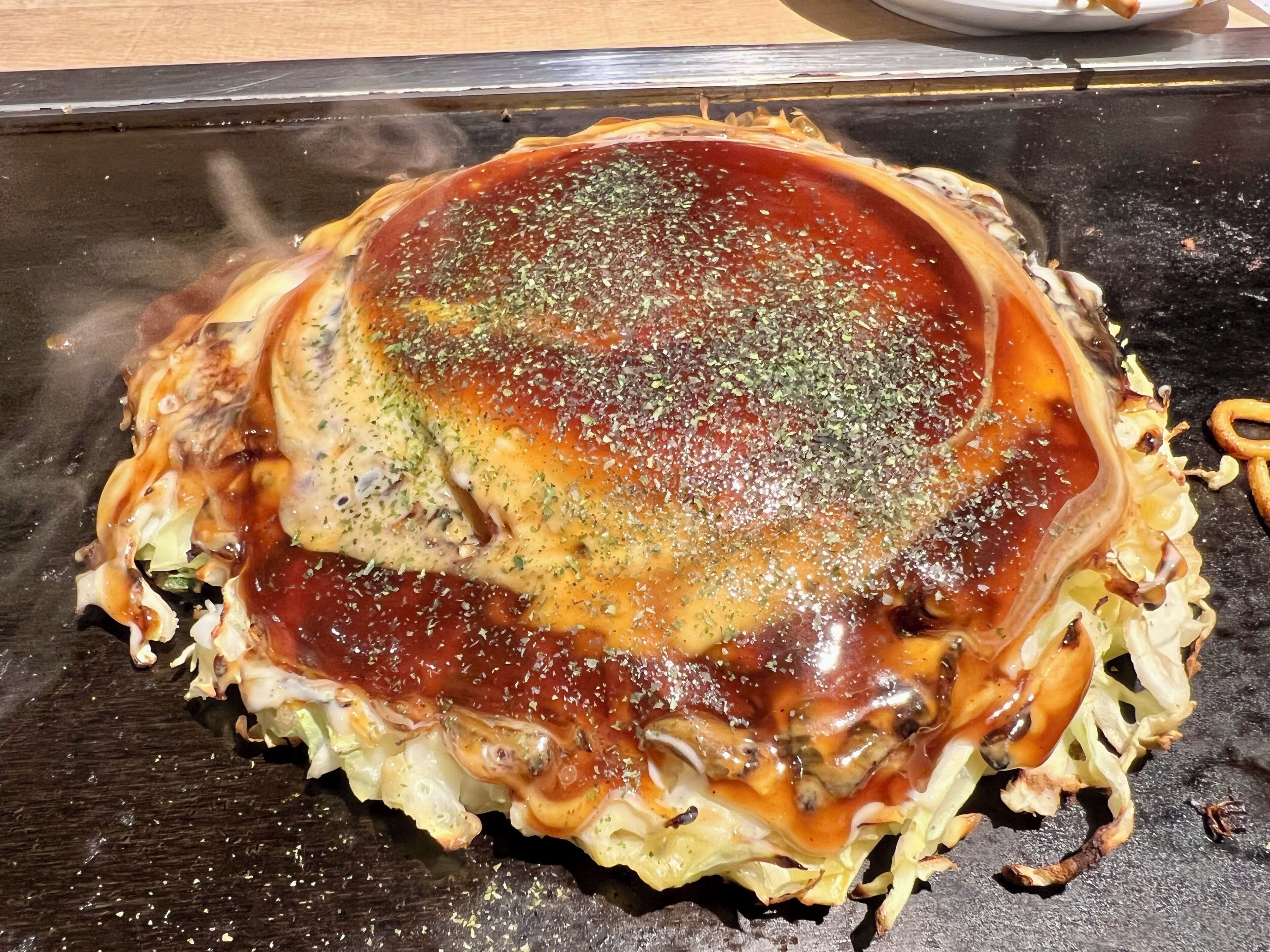 A dish with a crispy edge, possibly a type of fried food, on a dark surface.