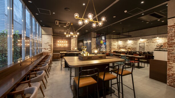 A modern restaurant with a long counter, multiple seating areas, and a brick wall. - Just Sleep Osaka Shinsaibashi (Osaka)