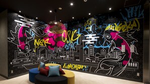 A modern interior with a vibrant graffiti mural, circular seating, and a cityscape design. - Just Sleep Osaka Shinsaibashi (Osaka)