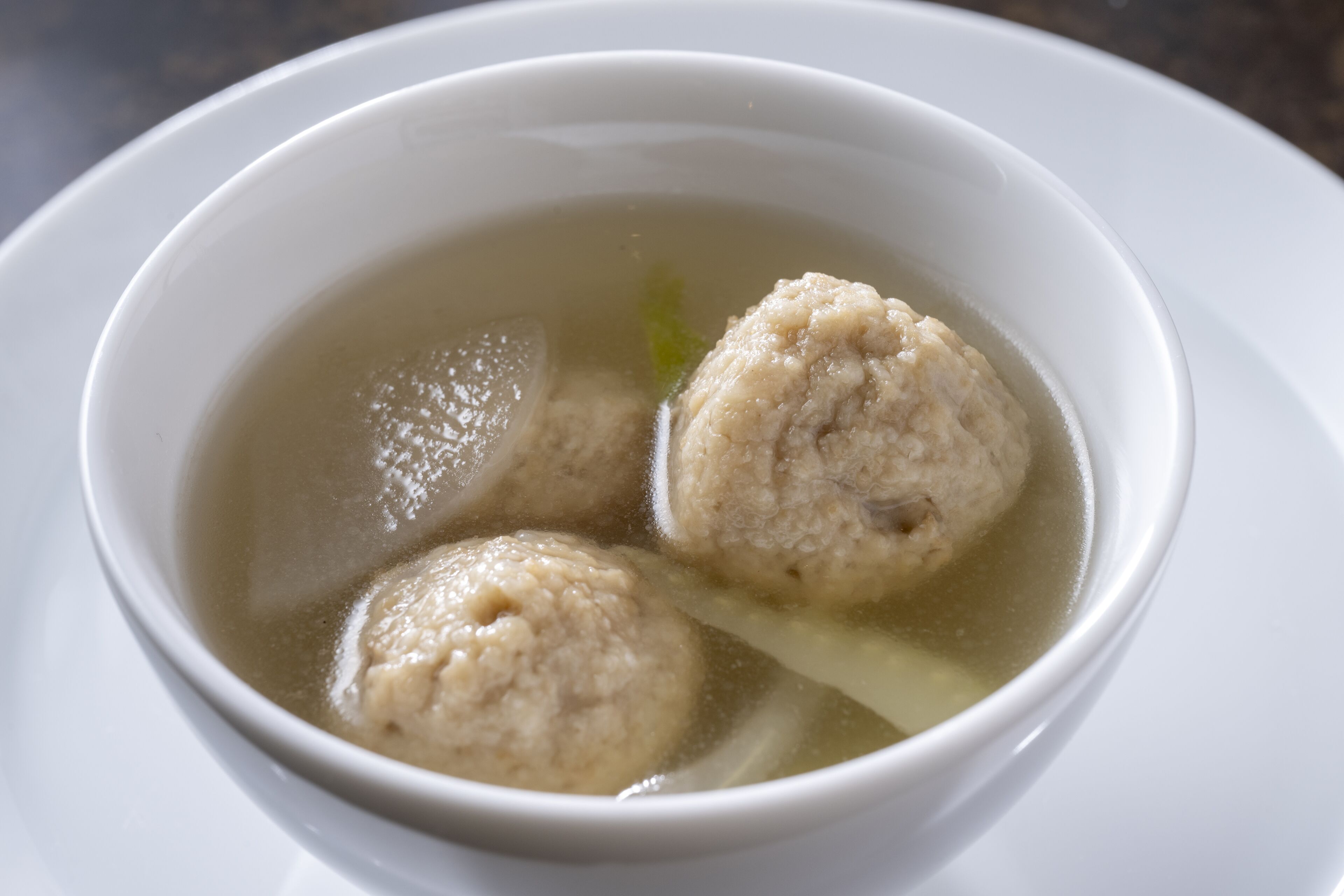 A bowl of soup with meatballs and a clear broth.