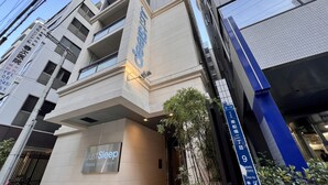 A hotel entrance with a 'Just Sleep' sign, a modern building facade, and a street sign indicating the address. - Just Sleep Osaka Shinsaibashi (Osaka)