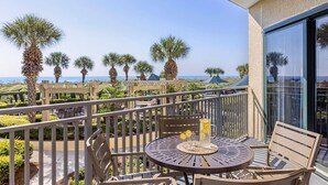 A balcony with a table and chairs, overlooking a beach with palm trees and a clear sky. - Oceanfront Villa! Marriott's Barony Beach Club - Family Friendly Resort - Right On The Beach! (Hilton Head Island)