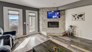 A living room with a stone fireplace, a flat-screen TV mounted above it, and a world map on the wall. - Sparrow's Nest - Stay at the lake, walk to Noah's Ark! (Wisconsin Dells)