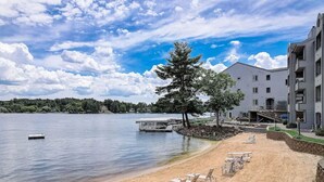 A lakeside hotel with a sandy beach, lounge chairs, and a dock. - Sparrow's Nest - Stay at the lake, walk to Noah's Ark! (Wisconsin Dells)