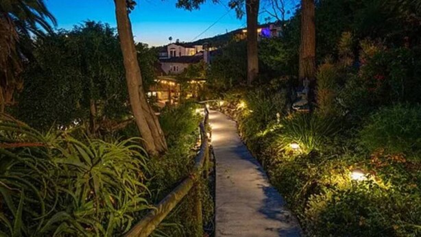 A pathway leading to a building surrounded by lush greenery and trees.
