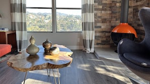 A modern living room with a large window, a brick wall, and a view of a cityscape.