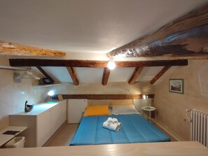 Ein kleiner, gemütlicher Raum mit Bett, Schreibtisch und Heizkörper.