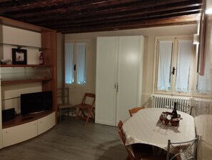 Ein gemütlicher Essbereich mit einem runden Tisch, Stühlen, einem Fernseher und einem weißen Schrank.