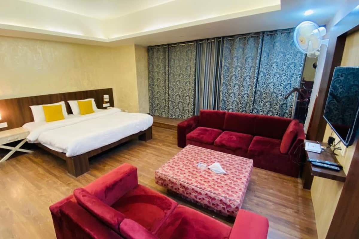 Ein Hotelzimmer mit einem Bett, einer roten Couch, einem kleinen Tisch und einem Fernseher.