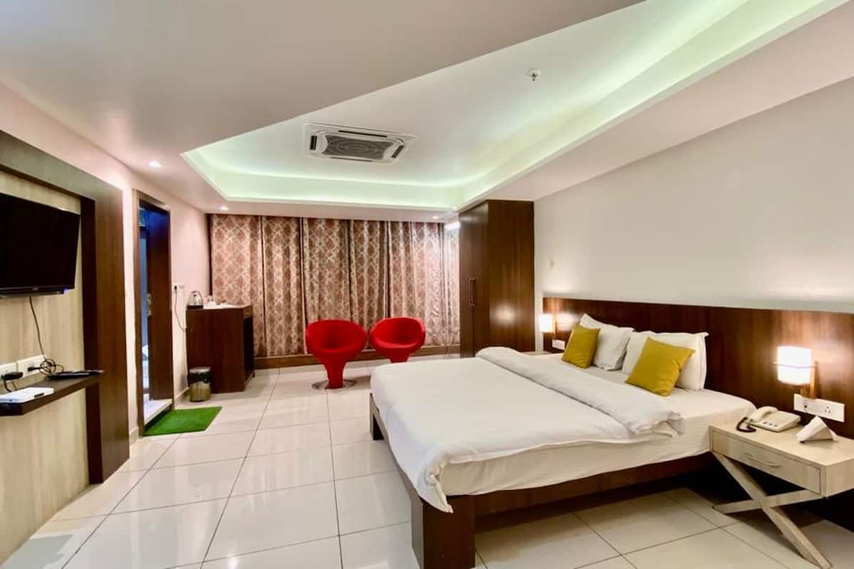 Ein Hotelzimmer mit Bett, Nachttisch, Fernseher und kleinem Schreibtisch mit Stuhl.