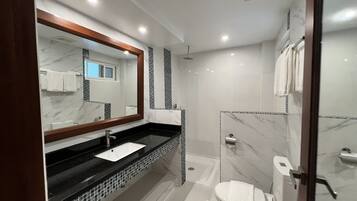 A modern bathroom with a black countertop sink, a large mirror, and a glass-enclosed shower area.