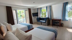 Habitación de hotel con dos camas, televisión, una mesita y un balcón con una silla.