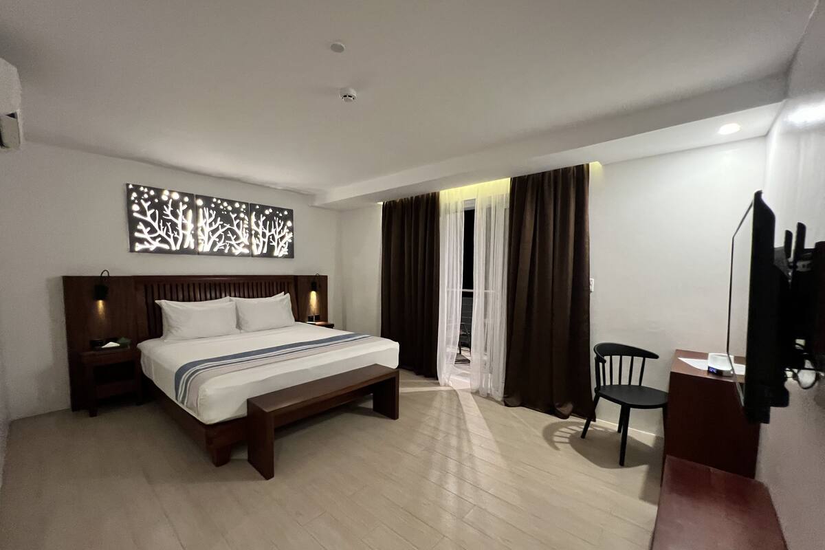 Ein Hotelzimmer mit einem Bett, einem Schreibtisch, einem Sessel und einem Fernseher.