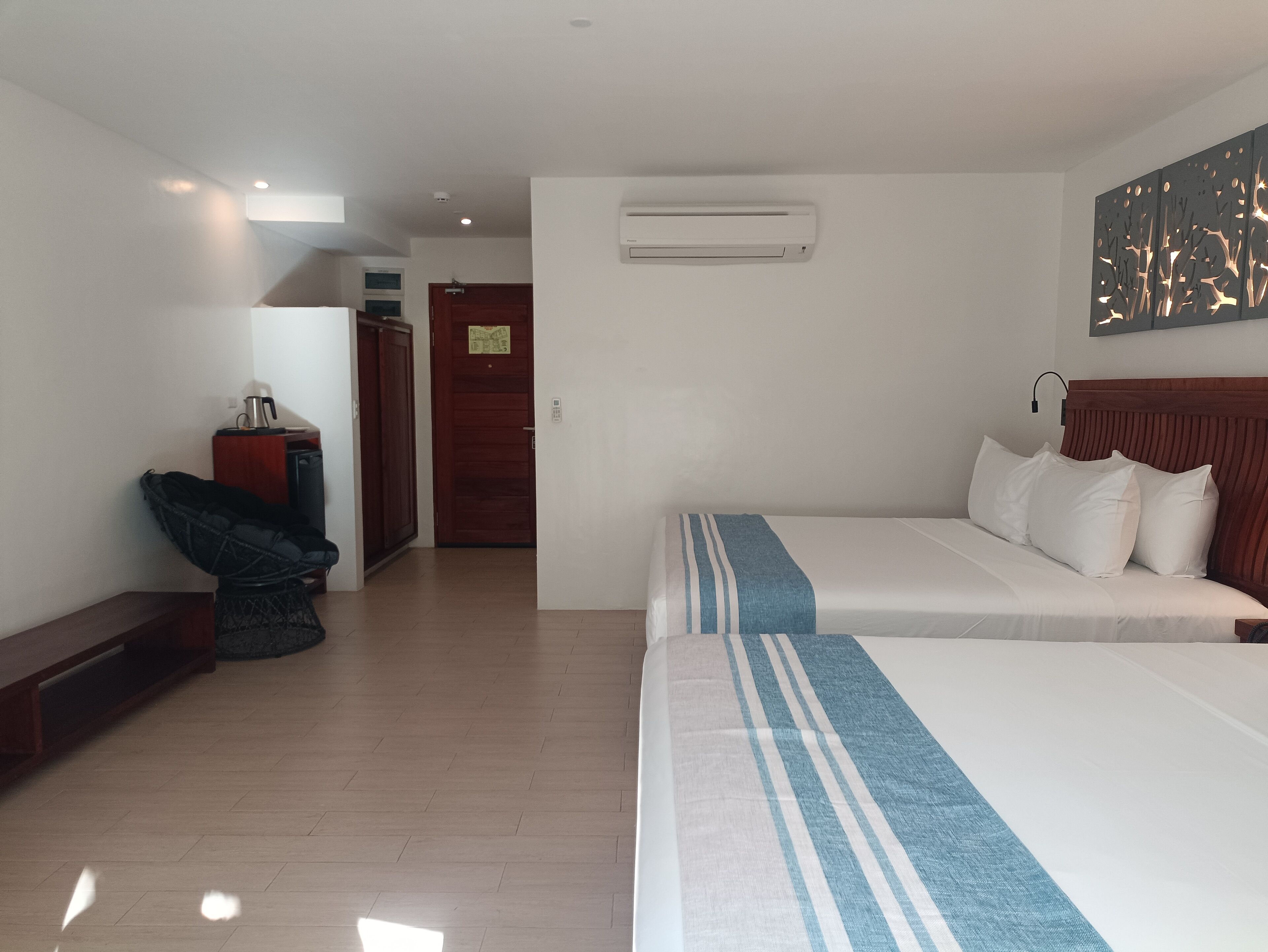 Une chambre d’hôtel avec deux lits, un bureau, une chaise et un appareil de climatisation.
