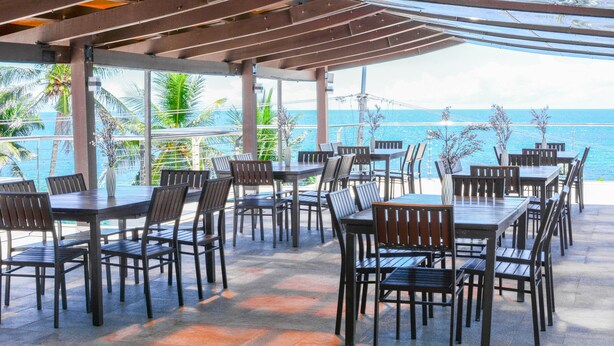 Un patio al aire libre con mesas y sillas, con vistas a un cuerpo de agua.