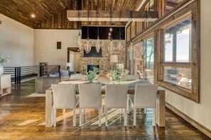 Un comedor amplio con una larga mesa, sillas y techo rústico.