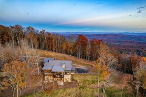 A house with a stone foundation, a metal roof, and a fenced yard. - Greystone Lodge - Hot tub & mountain views (Mineral Bluff)