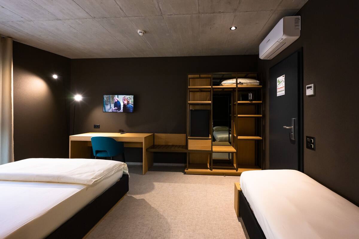 Une chambre d’hôtel avec deux lits, un bureau, une télévision et une armoire.