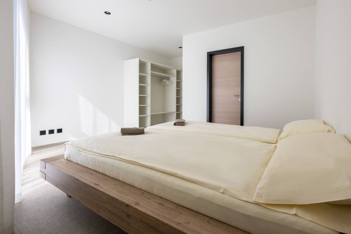 Une chambre moderne avec un grand lit, des étagères intégrées et une porte en bois.