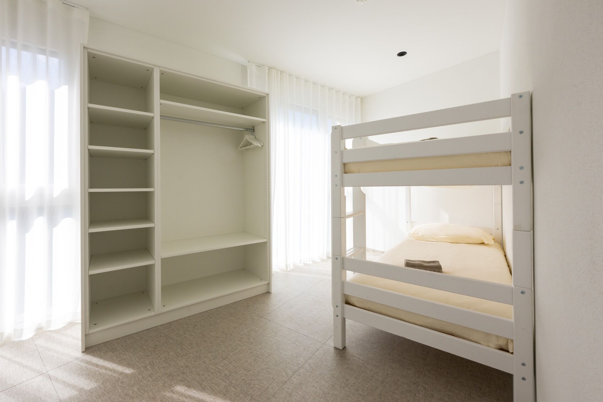 Una cama litera con estructura blanca y un vestidor con amplias repisas.