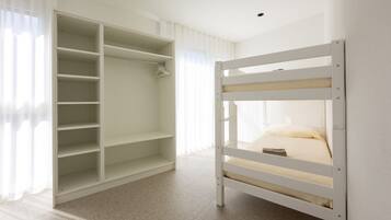 Una cama litera con estructura blanca y un vestidor con amplias repisas.
