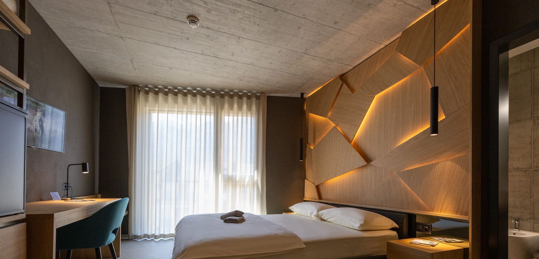 Une chambre d’hôtel moderne, dotée d’un grand lit, d’un bureau et d’une chaise.