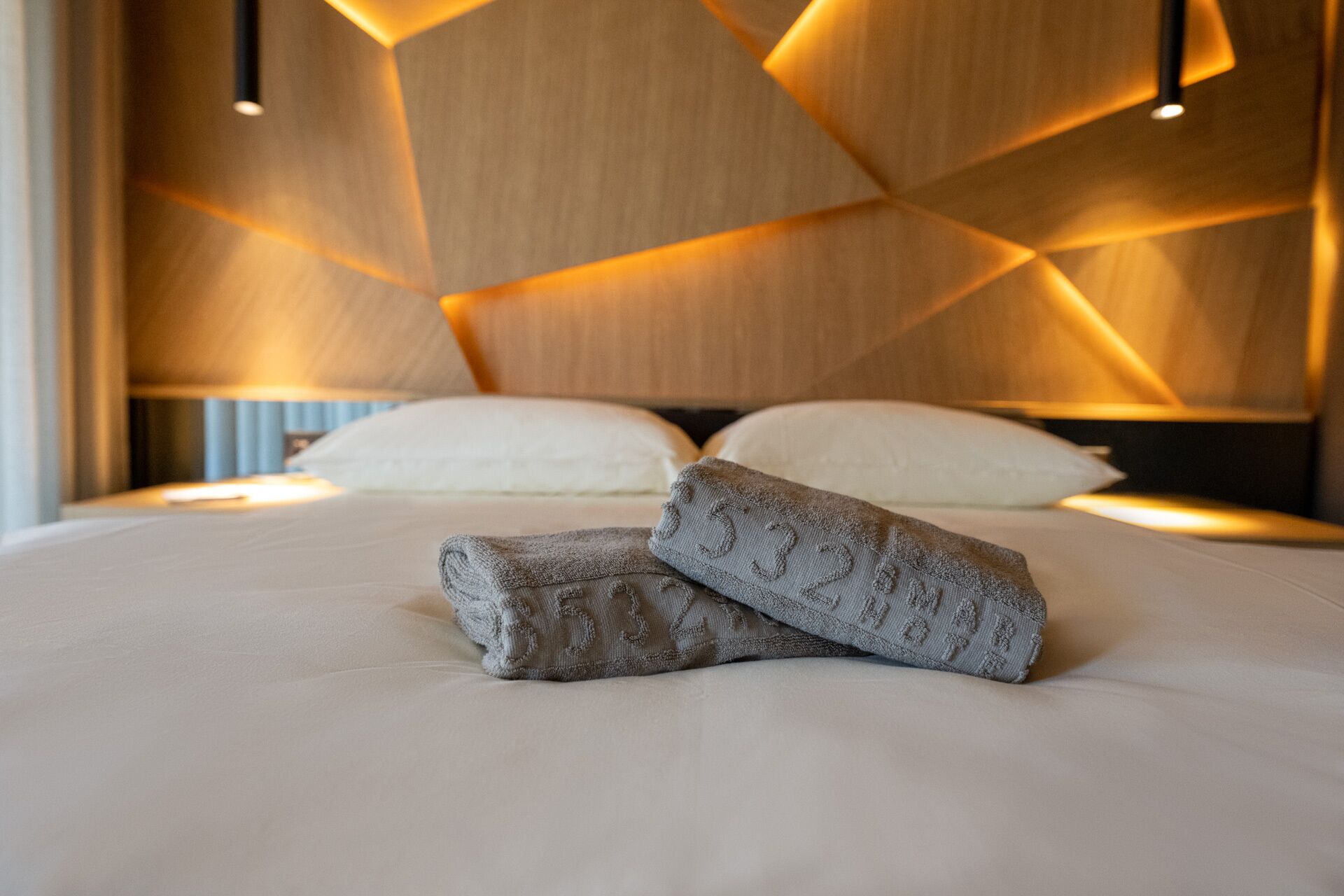 Una cama bien hecha con dos almohadas y dos toallas dobladas al frente.