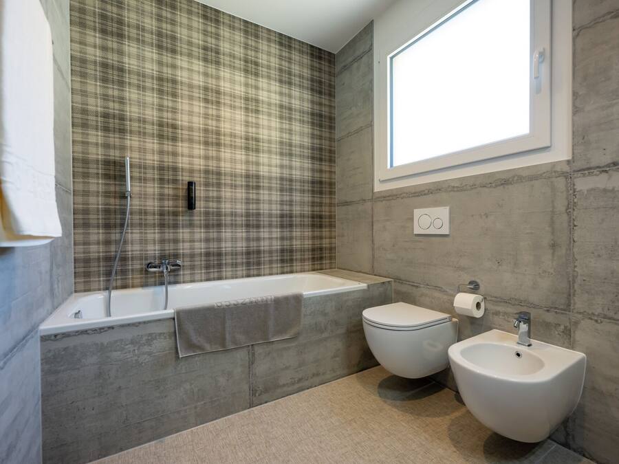 Un baño moderno con una bañera grande, un inodoro y dos bidés.