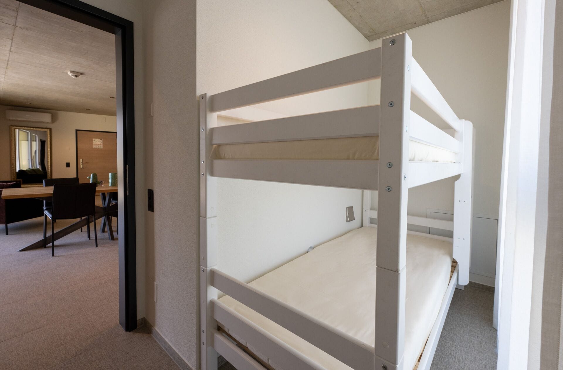 A bunk bed room with a desk and chairs in the background.