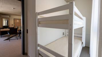 A bunk bed room with a desk and chairs in the background.