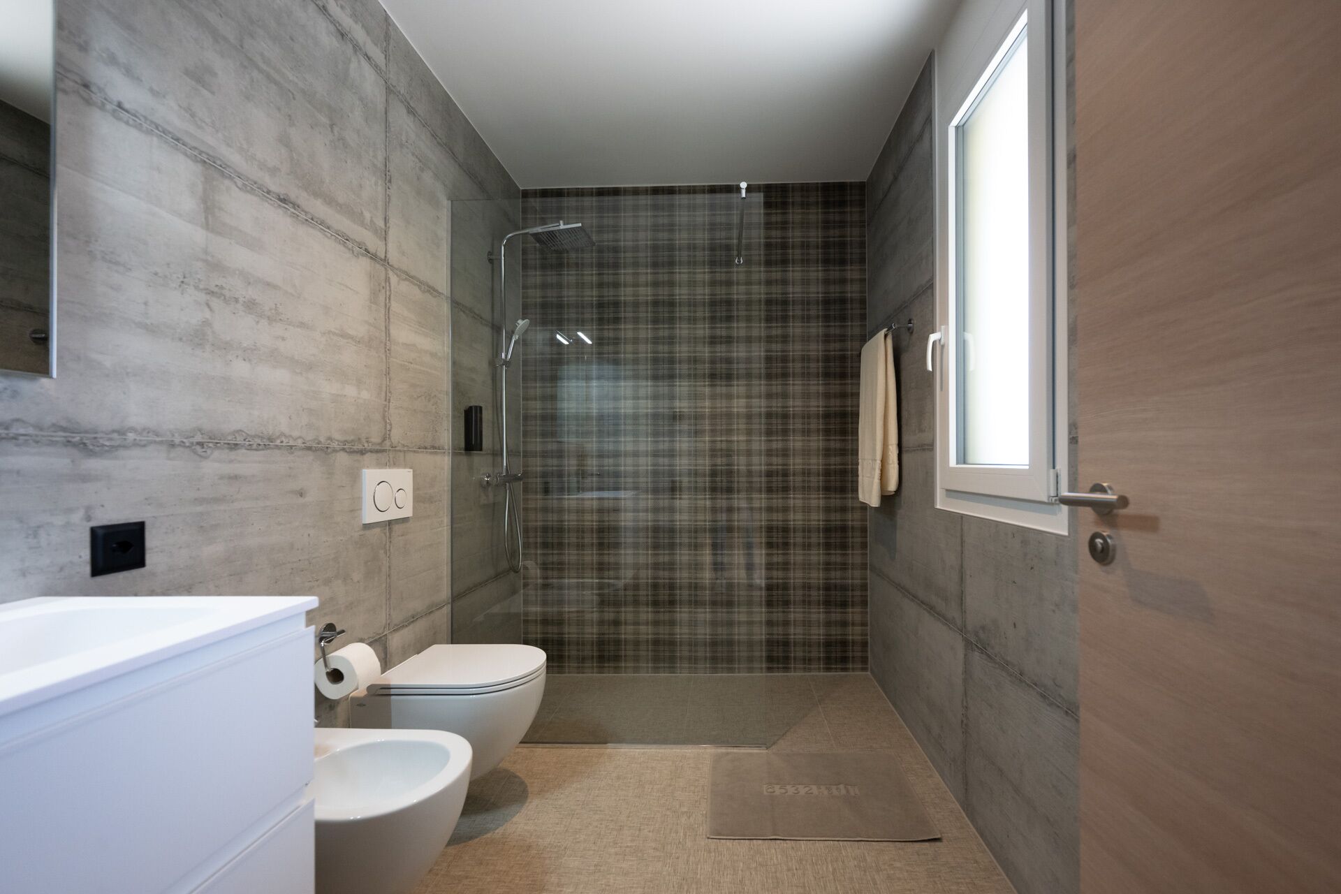 A modern bathroom with a shower, toilet, and bidet.