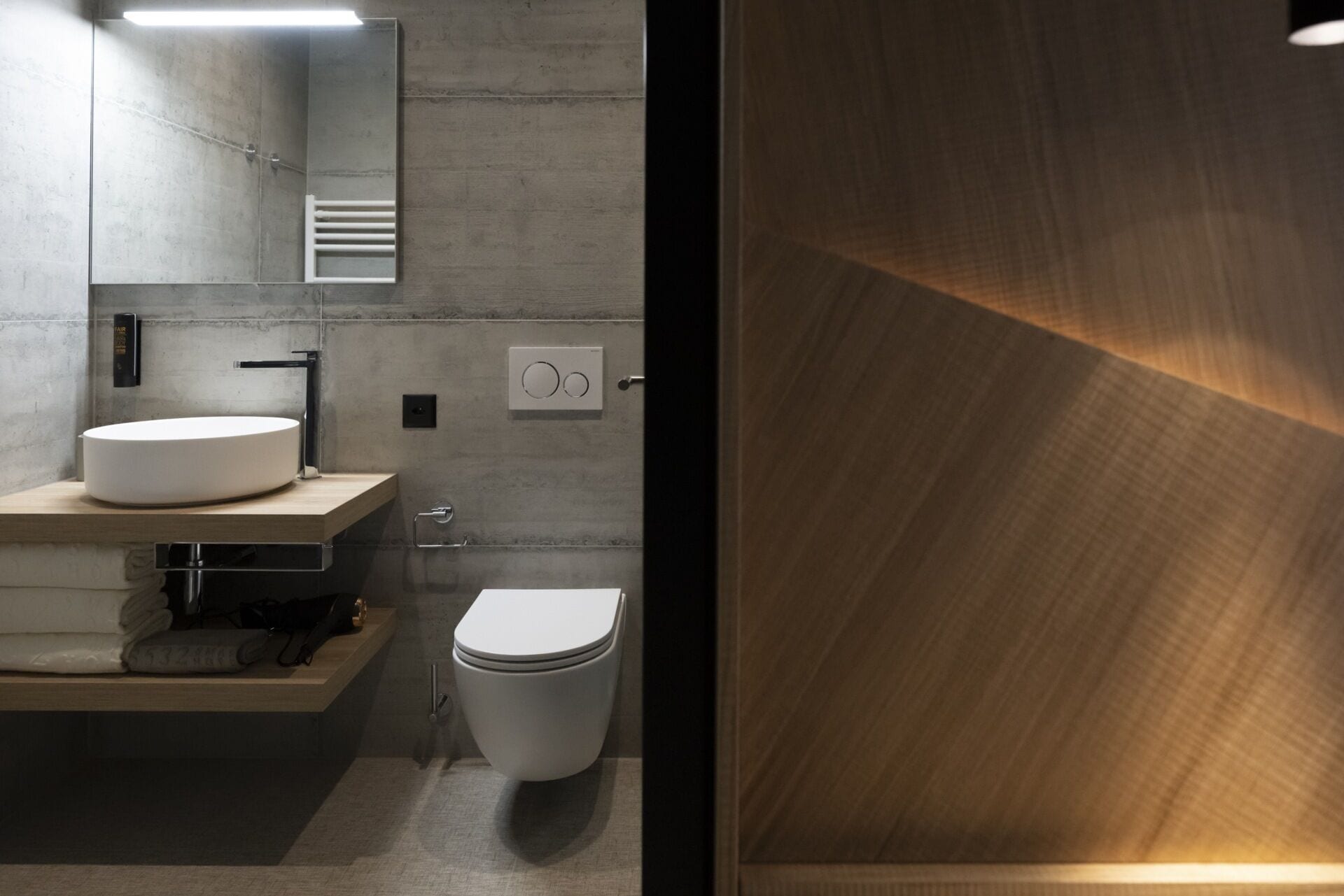 A modern bathroom with a round sink, a toilet, and a mirror.