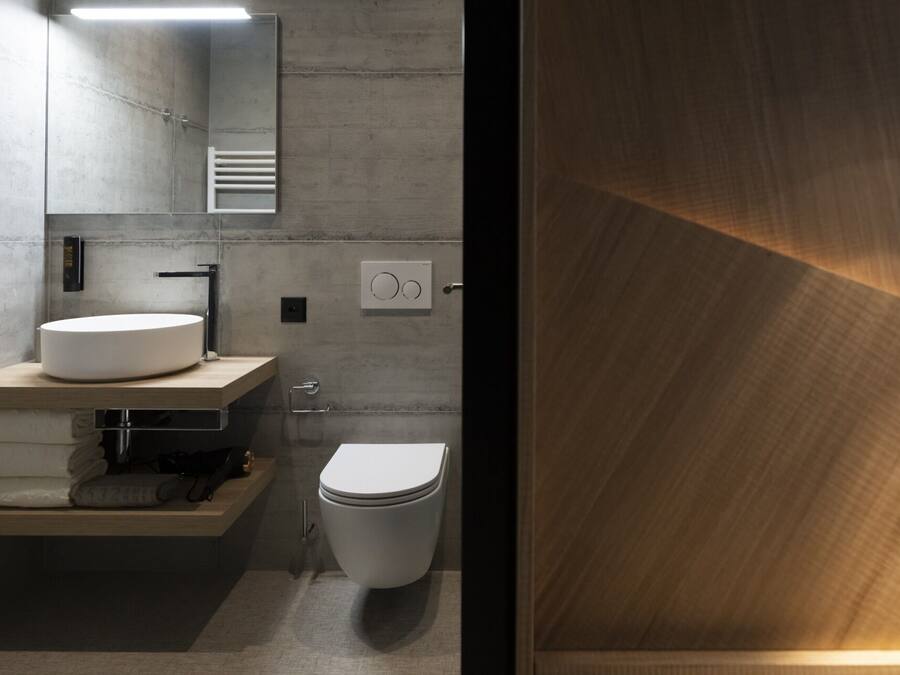 A modern bathroom with a round sink, a toilet, and a mirror.