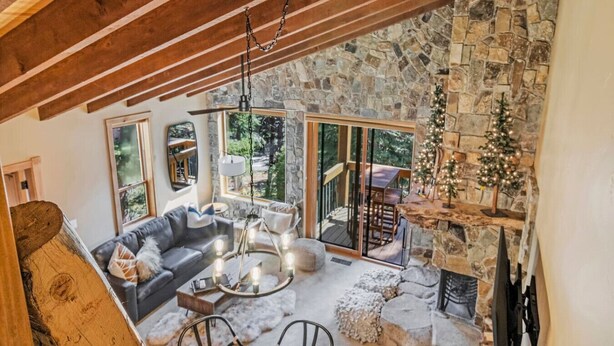 A cozy interior with a stone fireplace, a wooden ceiling, and a view of the outdoors.