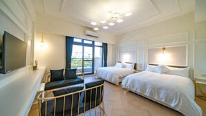 Habitación de hotel con dos camas, un sofá, un televisor y un balcón con vistas.