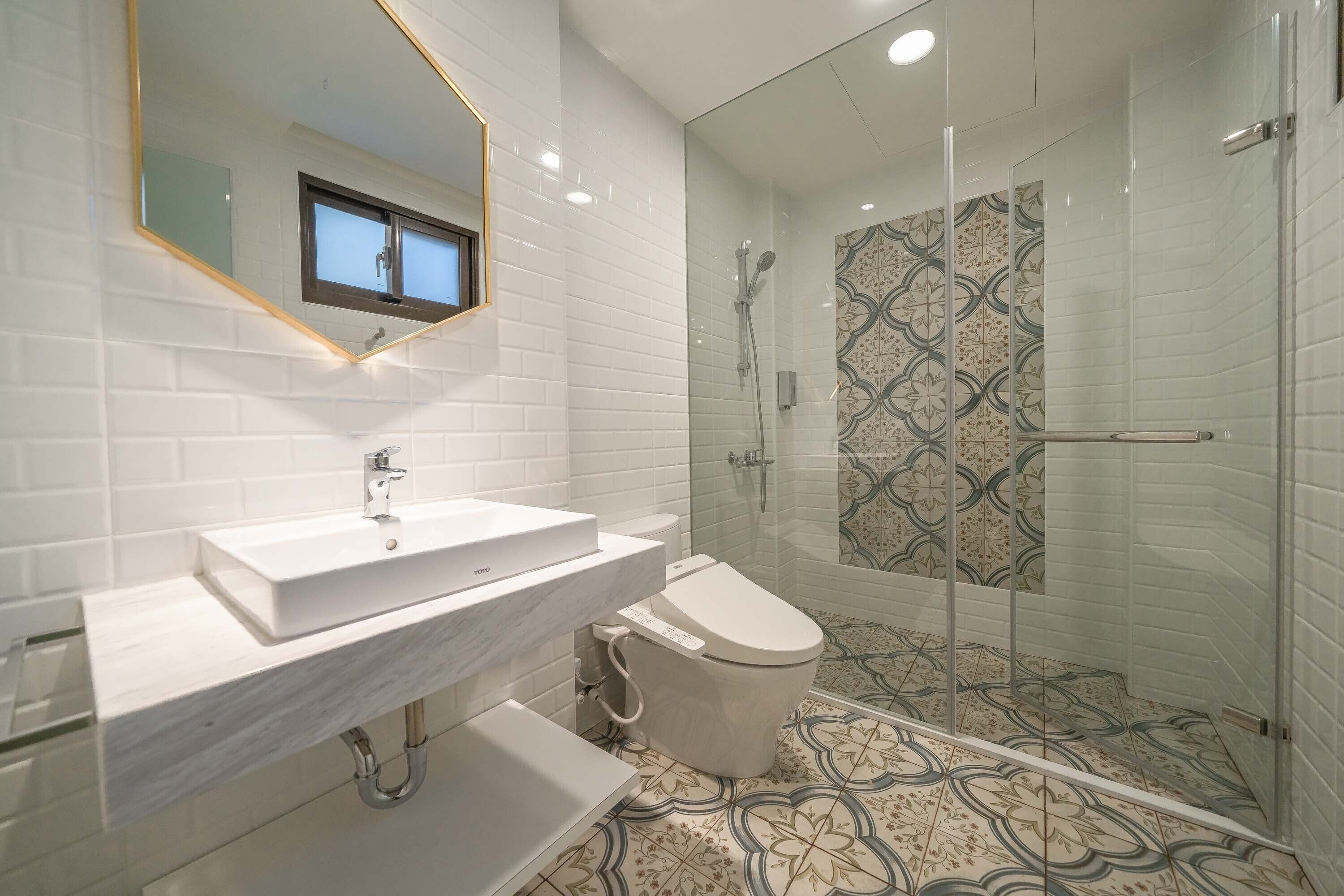 A modern bathroom with a white sink, toilet, and glass-enclosed shower.