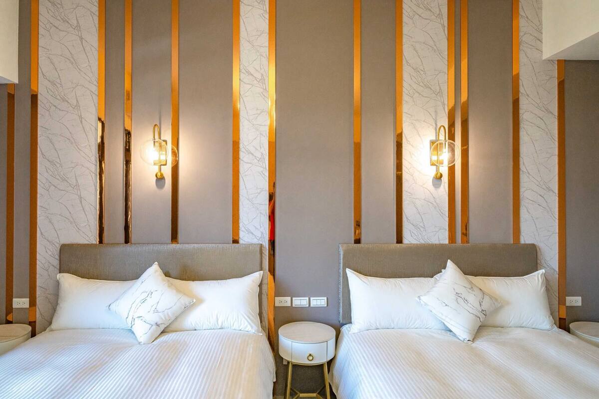 A hotel room with two beds, a small round table, and wall-mounted light fixtures.