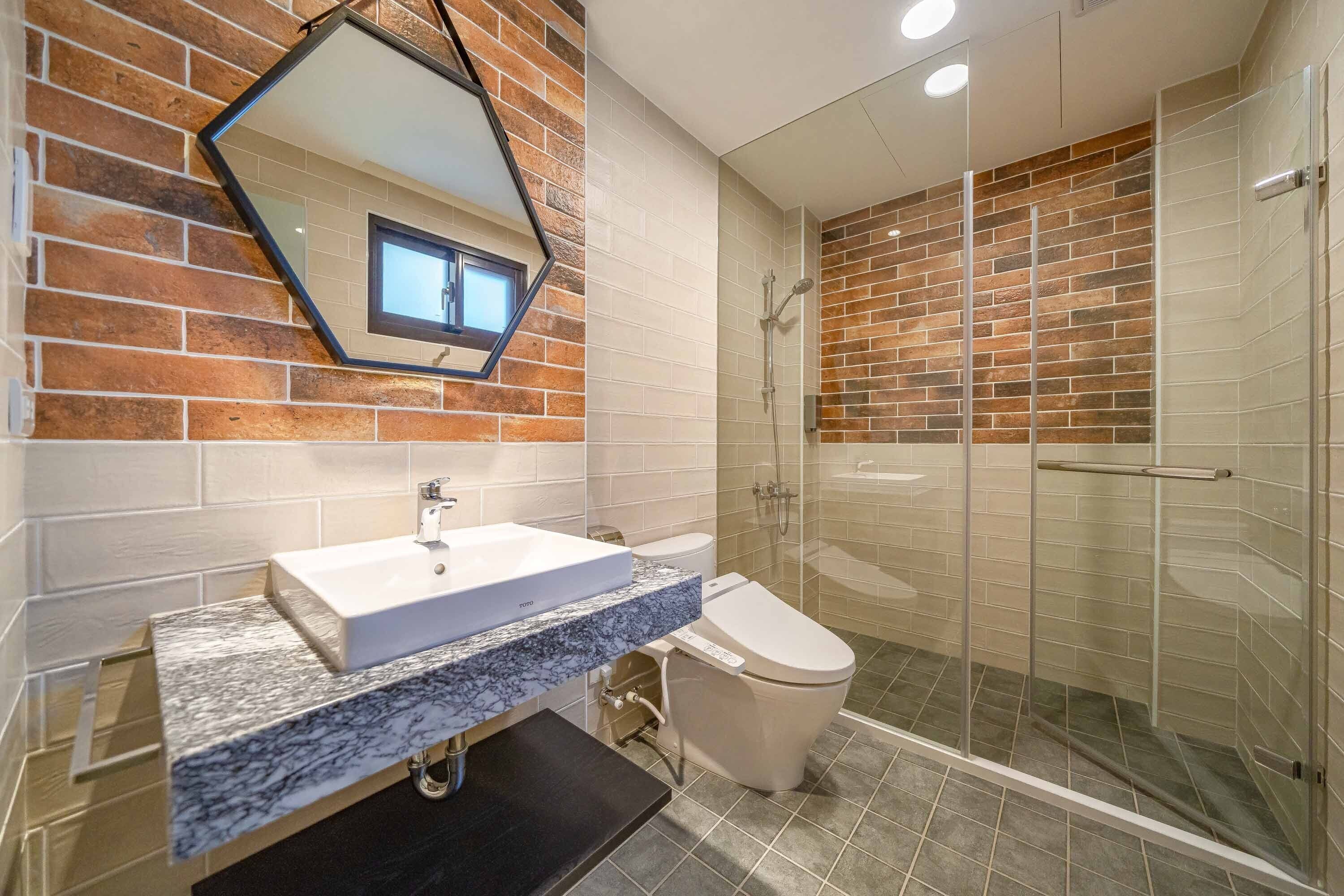 A modern bathroom with a marble sink, a toilet, and a glass-enclosed shower.