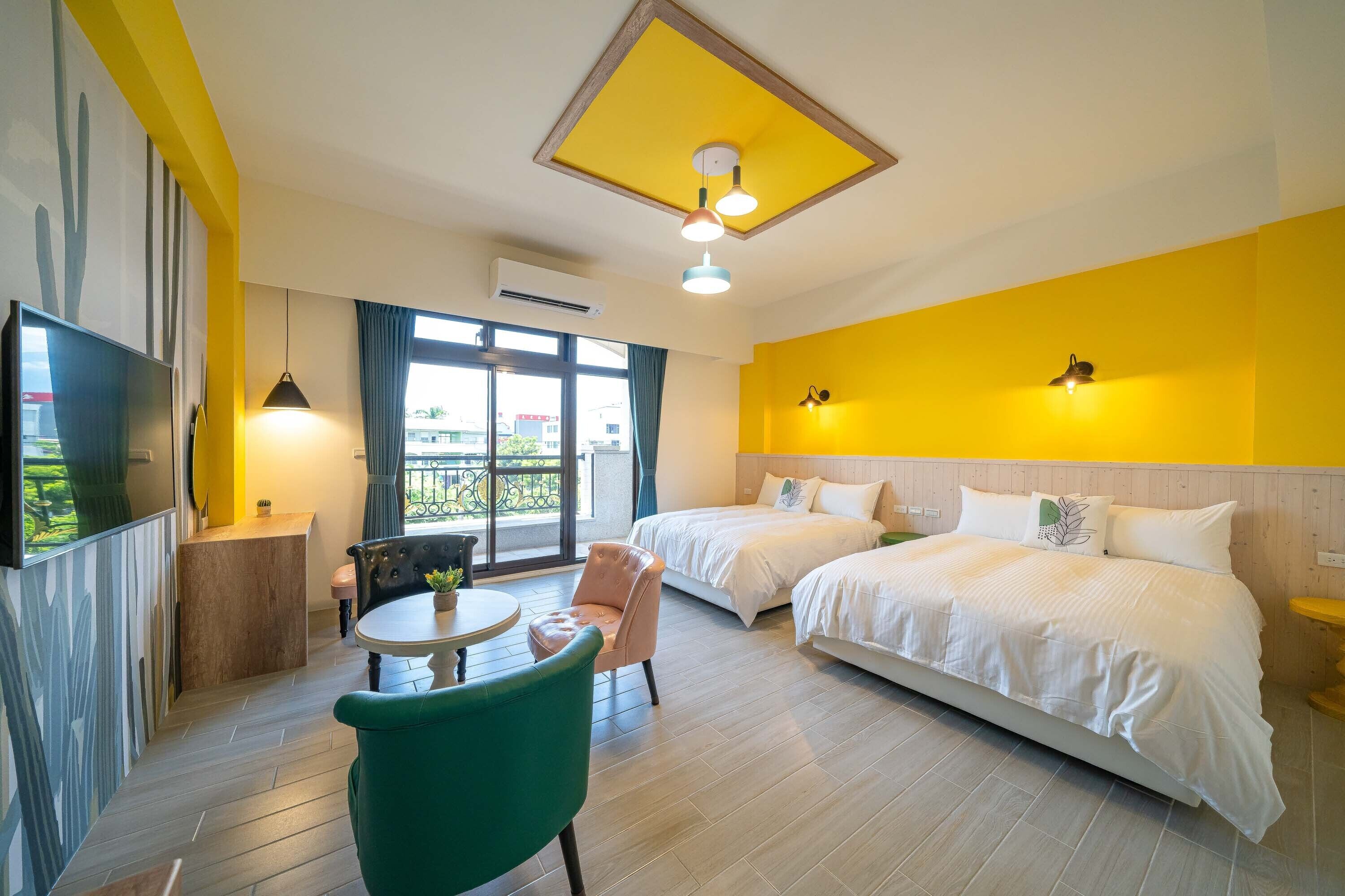 A hotel room with two beds, a TV, a desk, a chair, and a balcony with a view.