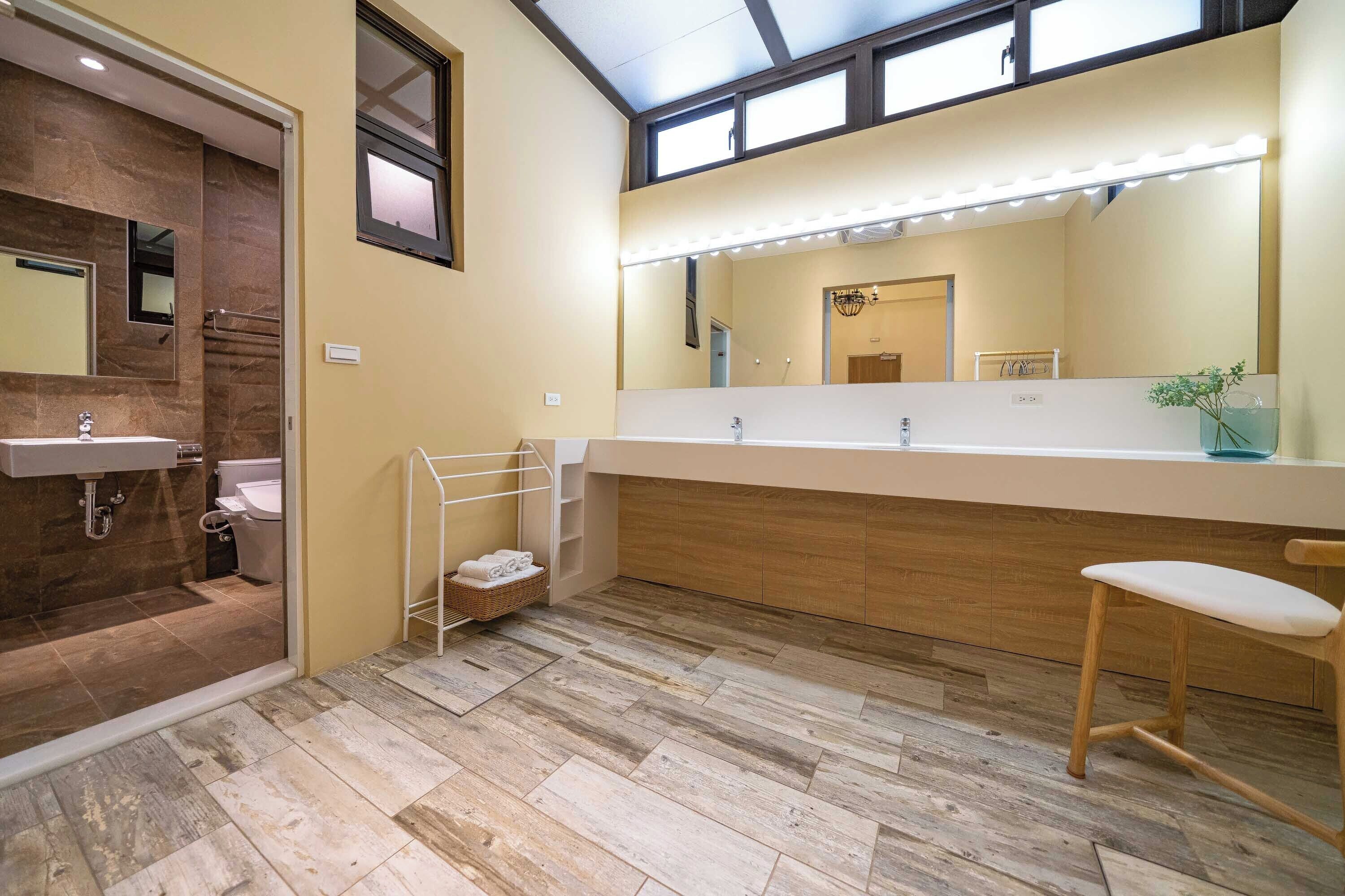 A modern bathroom with a large mirror, vanity, and a wooden floor.