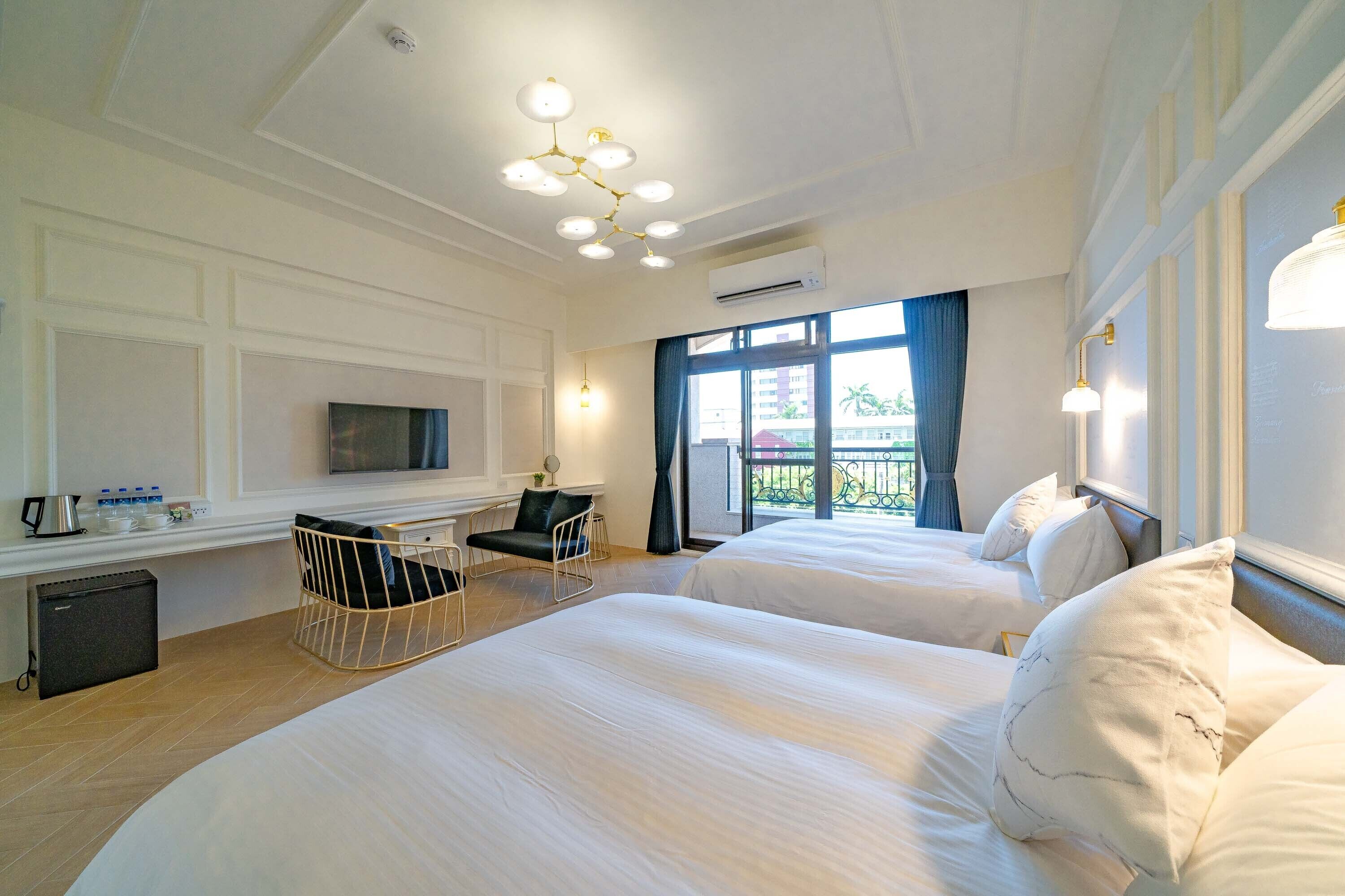 Ett hotellrum med två sängar, ett skrivbord, en stol, en tv och en balkong med utsikt.