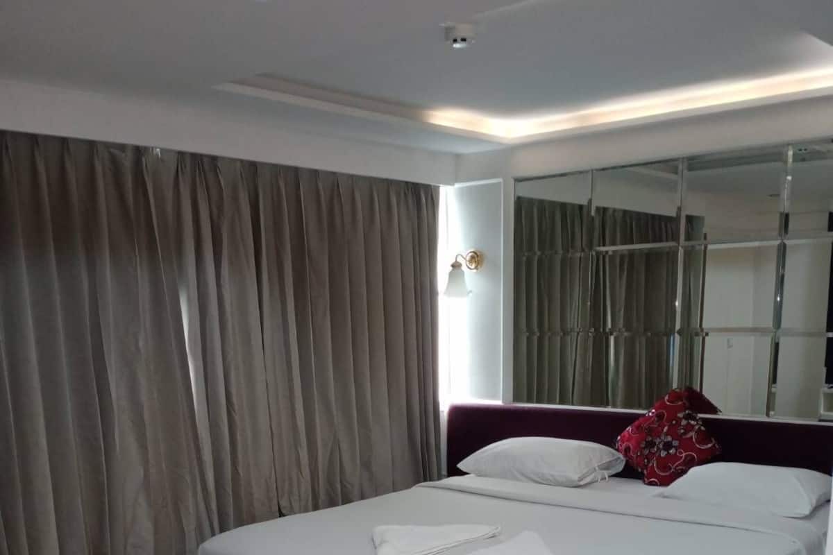 Ein modernes Hotelzimmer mit einem großen Bett, Holzboden und einem großen Spiegel.