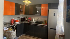 A modern kitchen with black and orange cabinets, a stainless steel refrigerator, a microwave, and a hanging light fixture. - 3 Bedroom Private vacation home in Pereybere (Pereybere)