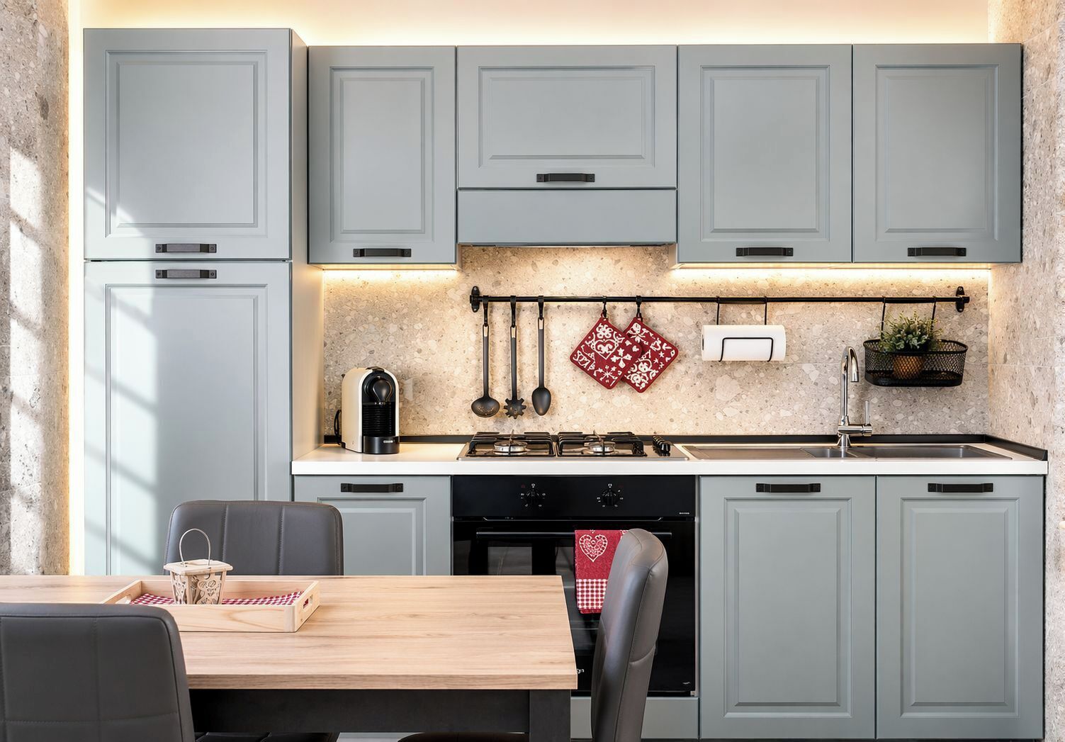 A kitchen with grey cabinets, a coffee machine, a stove, and a sink.