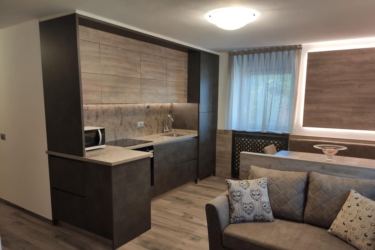 A modern kitchen with a built-in microwave, a sink, and a dining area with a sofa and a glass bowl.