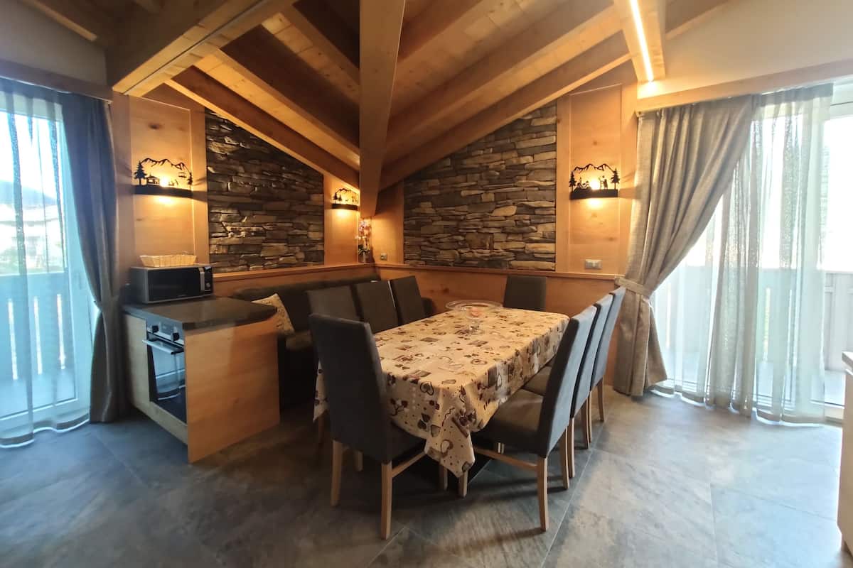 A dining area with a wooden table, chairs, and a stone wall.