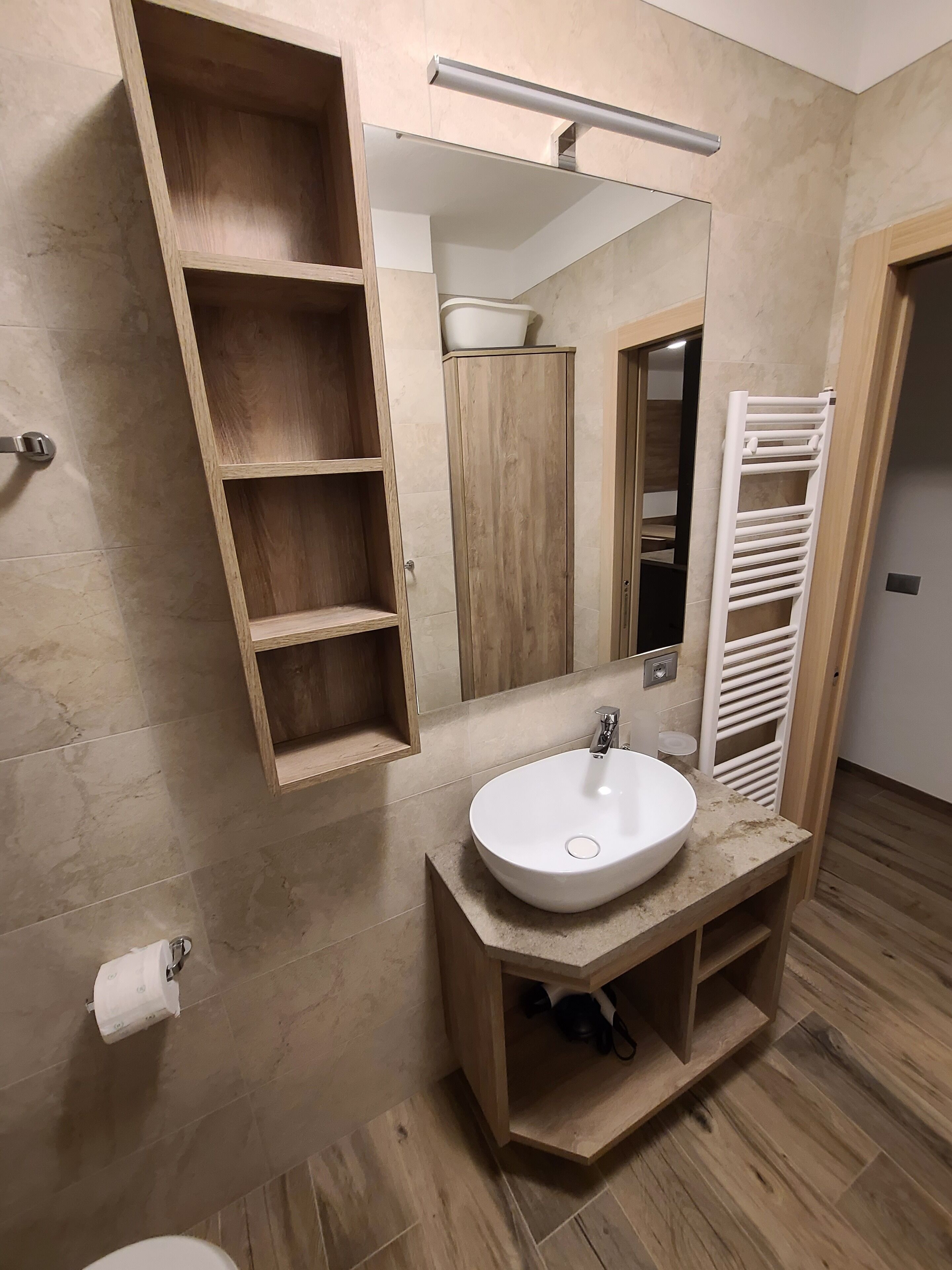 A bathroom with a wooden vanity, a white sink, and a mirror.