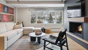 A modern living room with a fireplace, a sofa, a coffee table, and a TV mounted on the wall. - Lodge Tower 486 2 BR at the base of Vail Mountain (Vail)